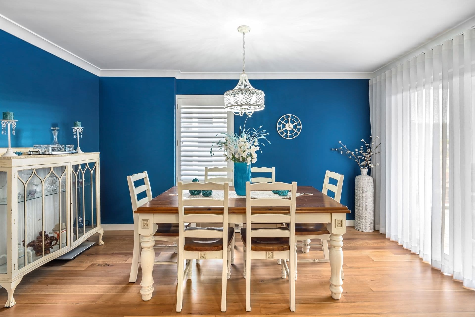 A dining room with deep blue painted walls, white trim, and crown molding