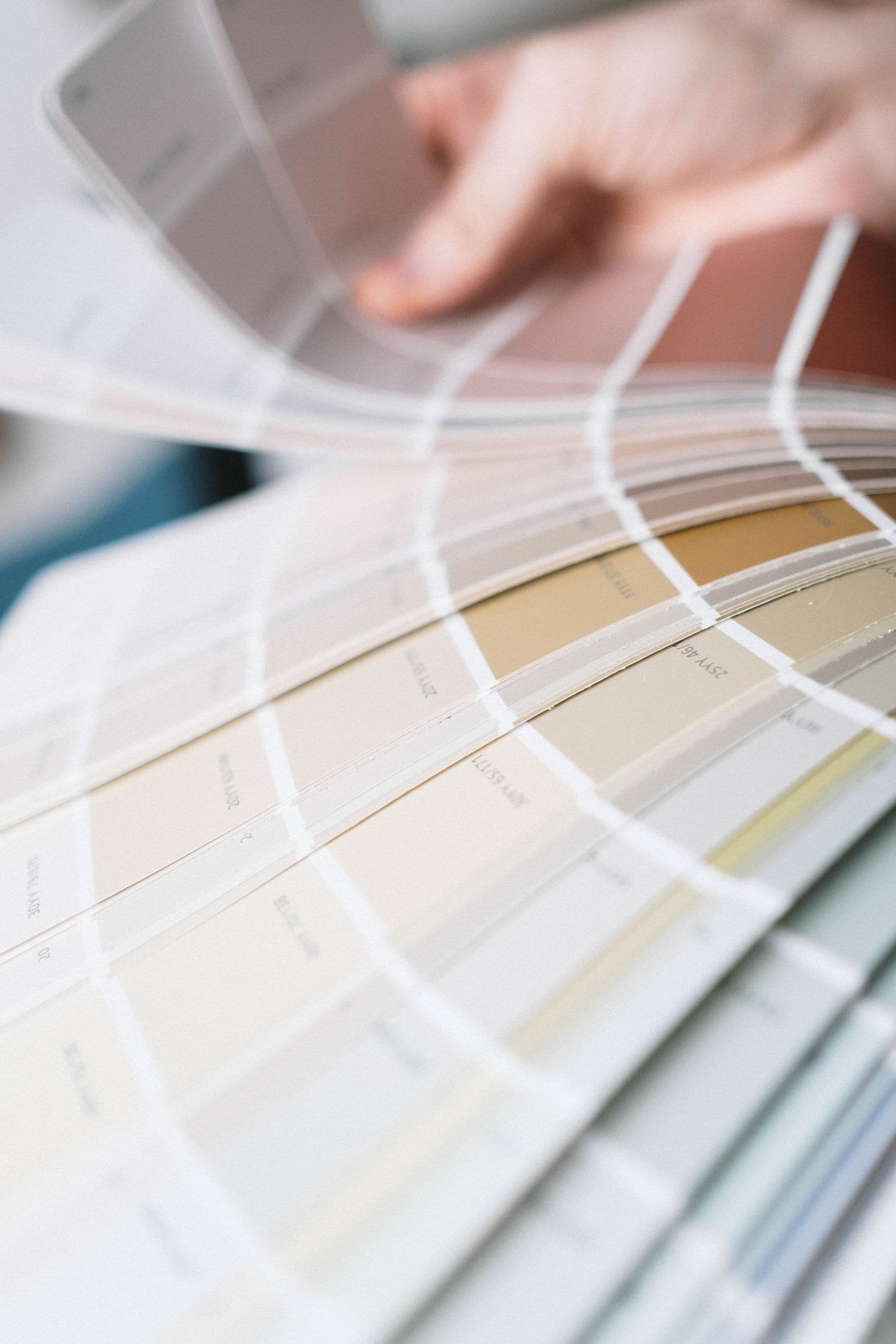 A hand fanning out decks of paint and stain color swatch cards